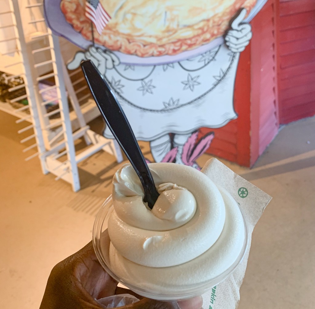 Holding a cup of soft serve maple ice cream in the shop